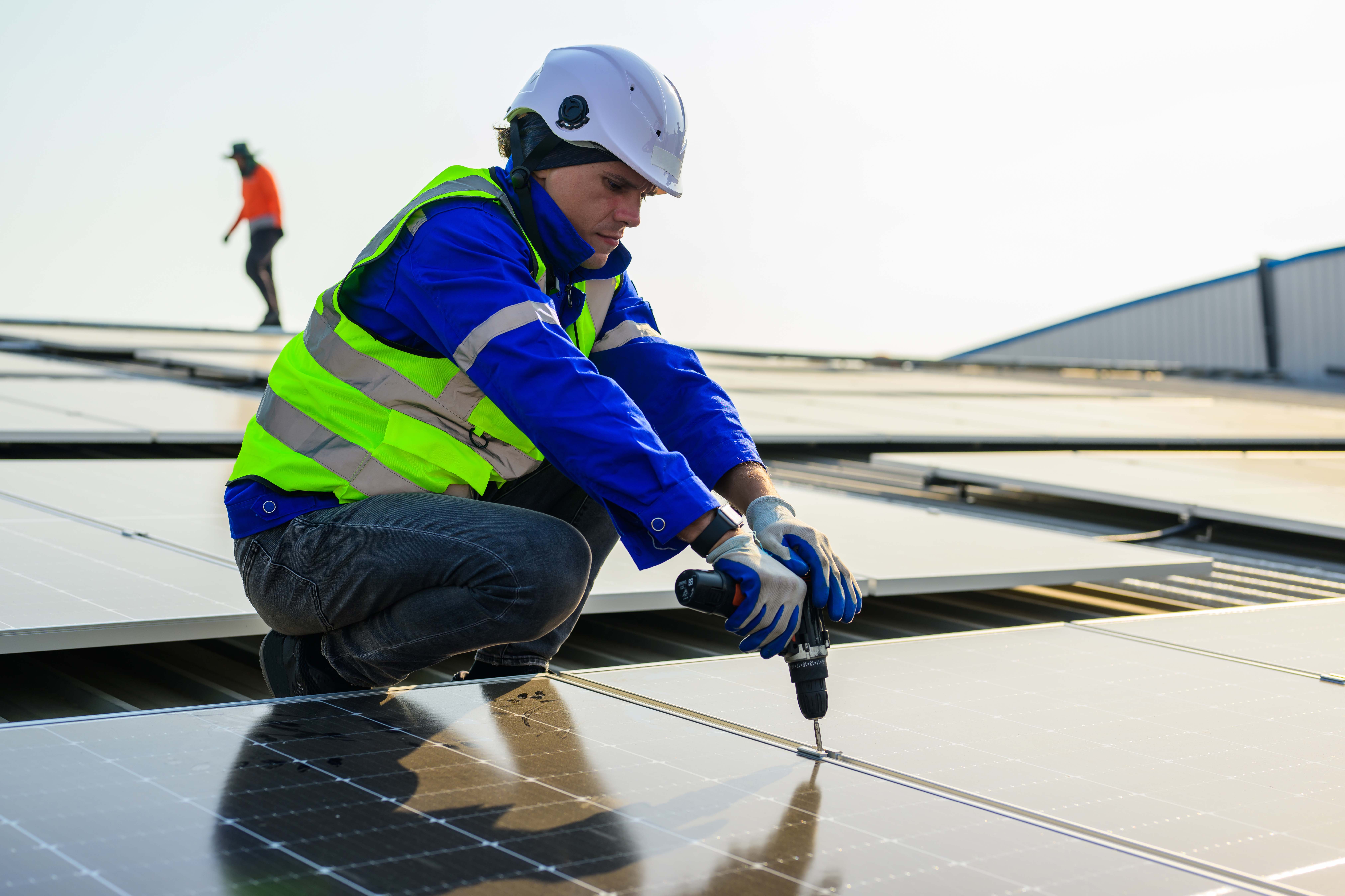 Person drilling solar panel onto business roof